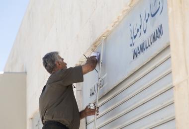 Calligrapher works on Crafts District signs at Raghadan Tourist Terminal